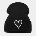 Dettaglio di un berretto in maglia nera con ricamo a cuore bianco sul bordo ripiegato - Taglia unica / Nero