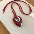 Detail of red water drop pendant necklace on cream book featuring silver metal accents - Necklace-Red