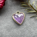 Detailed view of faceted heart-shaped purple crystal pendant with gold plating on felt - Purple