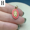 Detailed close-up of an oval gold religious pendant with pink enamel border and icons - Pink