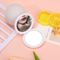 White round foldable pocket mirror with double-sided design on pink background - White