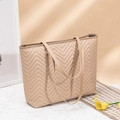 Dettaglio della borsa tote trapuntata beige con cuciture a V su marmo - Cachi