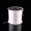 Transparent elastic crystal string roll for DIY jewelry beading on black background - White