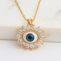 Vue détaillée du collier Œil Maléfique doré serti de zircons sur fond de marbre blanc - Bleu