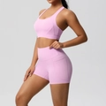 Detailed view of pink yoga bra and high-waisted shorts with side pockets on model - Sakura Pink