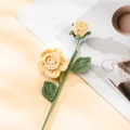 Detail der handgestrickten gelben Rose mit grünem Stiel auf Buch, kreative Garnblume - Gelb