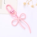 Dettaglio del portachiavi a fiocco in metallo rosa con chiusura a moschettone su bianco - Rosa