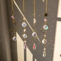 Four crystal suncatchers with raw stones and geometric brass frames casting rainbows - Amethyst 4-Piece Set