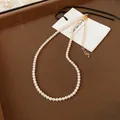 Close-up of pearl necklace featuring gold-plated lobster clasp and adjustable link chain - 6mm / Gold-White