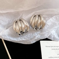 Macro detail of silver tiered knot earrings with textured grooves and polished finish - Silver