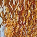 Detail view of orange gold foil fringe curtain with star cutouts and wavy stripes - Ceramic-Look S-Shape (PVC Decoration) / Orange