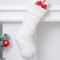 White knitted Christmas stocking with cable texture and gift box inside on a white mantel - White