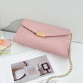 Borsa a tracolla rosa motivo litchi con catena dorata sopra una rivista - Rosa