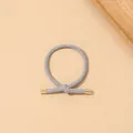 Close-up of a grey elastic knotted hair tie with premium golden metal accents and woven texture - Ribbed Knot - Metal Buckle / Gray
