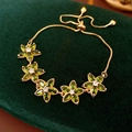 Macro view of five-flower zircon bracelet with olive green stones and adjustable clasp - Green Gold