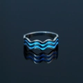 Macro view of wave-shaped stainless steel ring with blue luminous inlay on black surface - US 8 / NY803 Wave Pattern