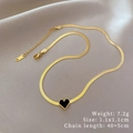 Collier chaîne serpent dorée avec pendentif coeur noir posé sur un tissu beige doux - Style Cœur Doré (N317)