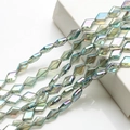 Close-up of diamond-shaped crystal glass beads with iridescent green and purple coating - Transparent Green