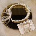 Detail eines weißen Perlen-Schmucksets mit Schleifenband und Kristallohrringen - Stirnband und Haarklammern Set