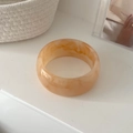 Minimalist wide geometric resin bangle with amber peach marble pattern on white desk - Beige