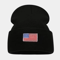 Detail of black knit beanie featuring a stitched American flag patch on a white background - One Size / Black