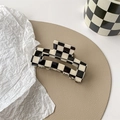 Detail view of the black and white checkerboard hair claw clip on a leather mat - Medium Square Claw