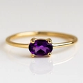 Primo piano di anello in ottone placcato oro con zircone viola ovale e montatura a quattro griffe - Viola