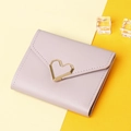 Detail of lavender tri-fold wallet with gold heart metal clasp on a yellow background - Purple