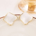 Close-up of geometric square studs with creamy marble texture and gold plating - White