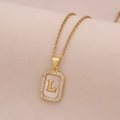 Gros plan du collier en or 18K avec pendentif nacre, lettre L et contour de diamants - Lettre L