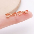 Golden pinch bails for pendants shown on a fingertip to illustrate the tiny size - 6x15mm / KC Gold