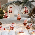 Christmas LED string lights with Santa Claus figures hanging on snowy pine branches - Santa Claus