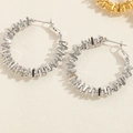 Detailed close-up of silver geometric spiral hoop earrings with interlocking metal strips - Textured Geometric Hoop Style