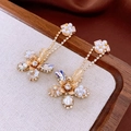 Detailed shot of vintage gold flower earrings with crystals, pearls and tassels on wood - Gold
