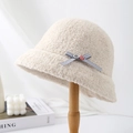 Close-up side view of a warm beige fluffy bucket hat with a delicate bow accent - Beige