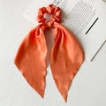 Elegant orange satin scrunchie with long ribbons and smooth texture on magazine - Orange Satin Ribbon