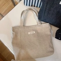 Close-up of minimalist off-white canvas tote bag with a simple wish fabric label - Solid Beige