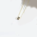 Minimalist gold necklace featuring a black square cube pendant with a golden letter X - Letter X