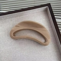 Dettaglio del fermaglio a mezzaluna color tè al latte su un vassoio di lino beige - Color Tè al Latte