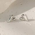 Minimalist silver heart stud earrings with a polished metallic finish on white texture - Heart Stud Earrings / Steel