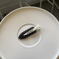 Detail of polka dot duckbill hair clip in iron shape on a white round display tray - Black Polka Dot Iron Shape - White Clip