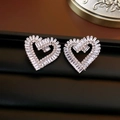 Dettaglio macro di orecchini a cuore in argento con zirconi scintillanti su pelle nera - Orecchini a lobo a cuore in zircone argento