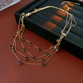 Détail du collier doré multi-rangs avec perles noires, fermoir mousqueton et chaînette - Or-Noir