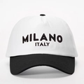 Detailopname van het zwarte MILANO ITALY borduursel op de witte katoenen honkbalpet - Wit en Zwart Splitsen