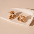 Detalle de pendientes de flor dorada con textura martilleada y una perla blanca central - Pendientes de flor dorada (aguja de plata)