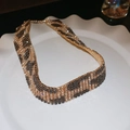 Detailansicht der breiten Halskette mit Strass-Leopardenmuster auf einem weißen Teller - Breiter Choker mit Leopardenmuster und Strass / Gold