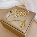 Nahaufnahme einer goldenen Planetenkette mit Kristallen auf einer beigen Schmuckbox - Goldener Planetenanhänger (J431)