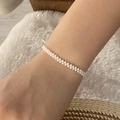 Close-up of white seed bead woven bracelet on wrist against a soft fuzzy background - White