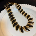 Parure de collier doré avec breloques en émail noir sur une assiette blanche en relief - 70# Collier Émail Noir Feuilles Or
