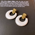Détail de boucles d'oreilles dorées à motif marbre sur fond de livre vintage - 9# Clous de Cercle Blanc Texture Marbre